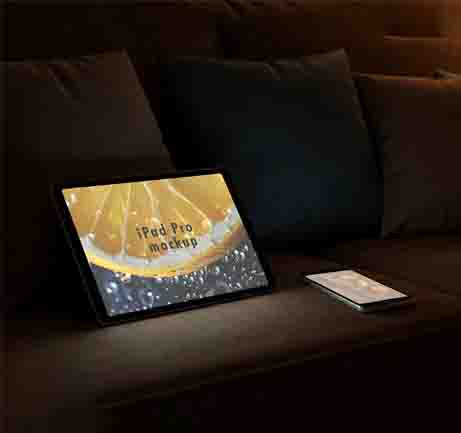 Free tablet and phone on sofa mockup in warm lighting